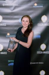 A person holds a trophy in front of a black backdrop with 'Edison Award' logos