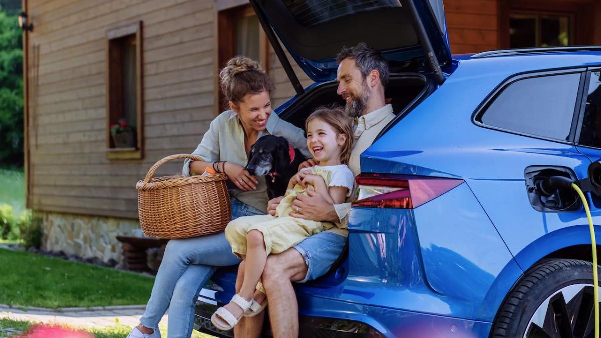 Family of three shown sitting in the back of an EV as it is being charged.