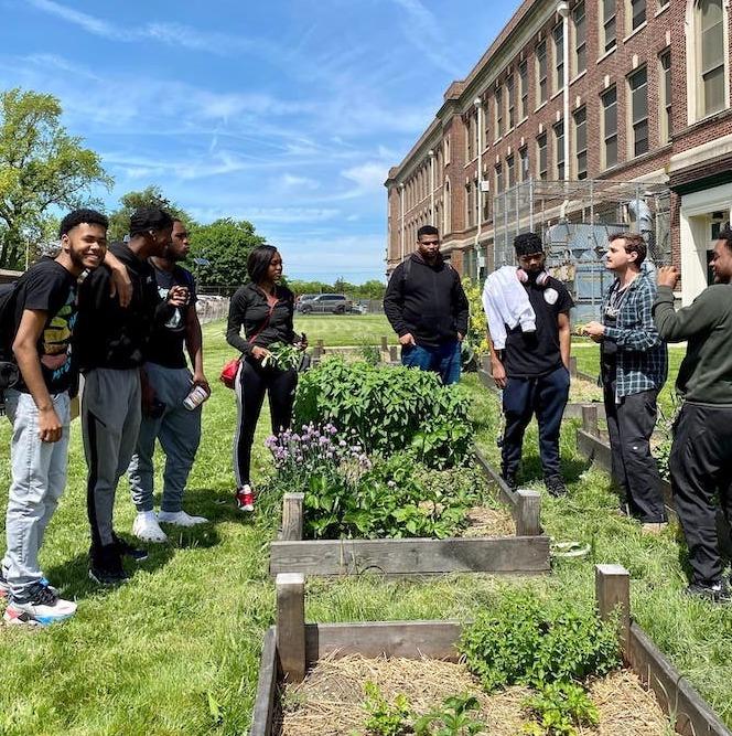 Several people standing around garden beds at Ellen DeGeneres urban farm