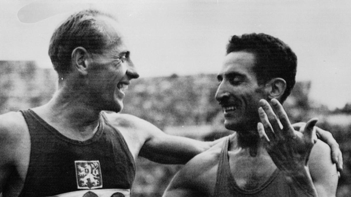 two runners smiling, one with their arm around the other