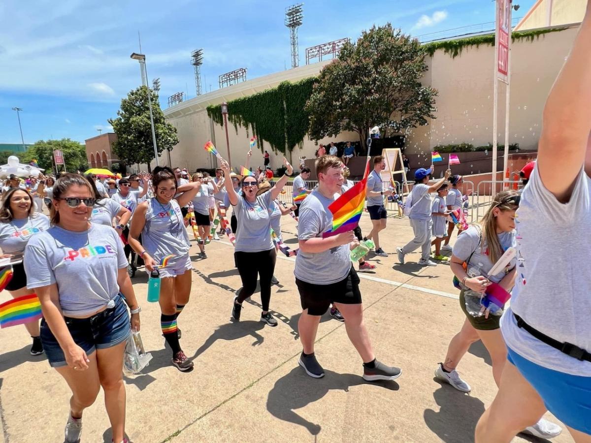 People marching in a parade, carrying rainbow flags