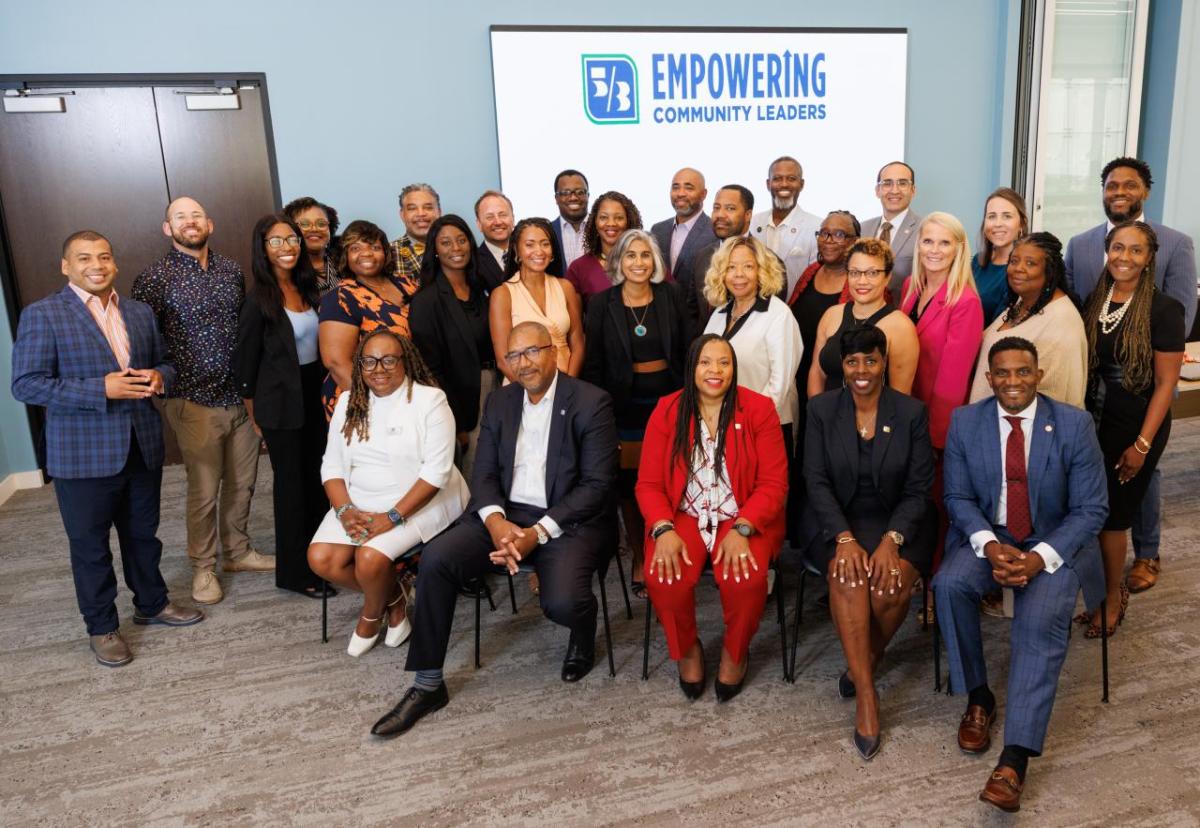 group of people smiling in front of Empowering Community Leaders sign