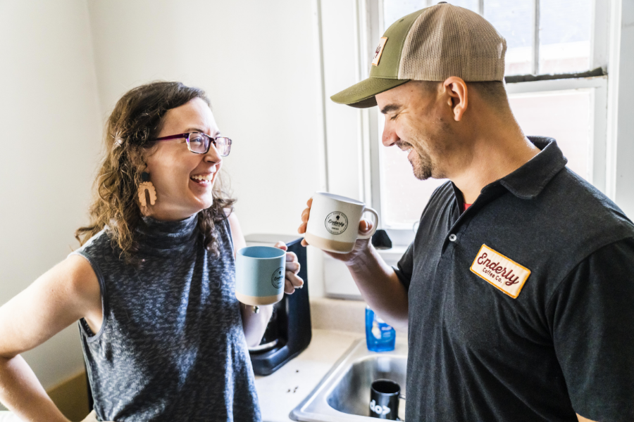 The Santoros laughing, holding coffee mugs.