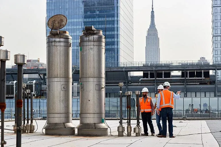 3 workers on a rooftop with the empire state building in the background