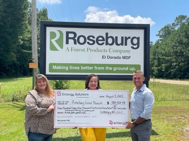 3 people holding a big check in front of a Roseburg sign