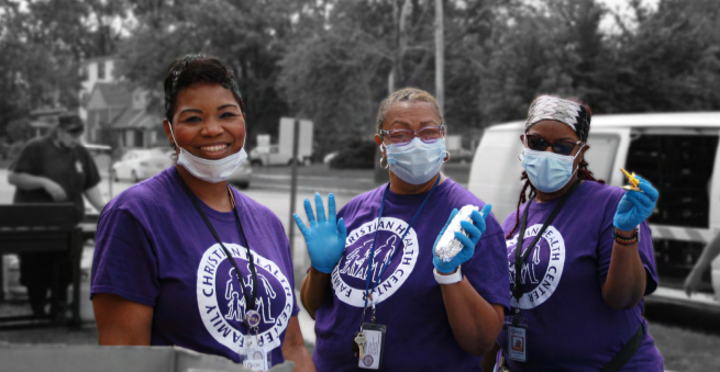 three people in protective masks and gloves outside. Each wearing a Family Christian Health Center tshirt.