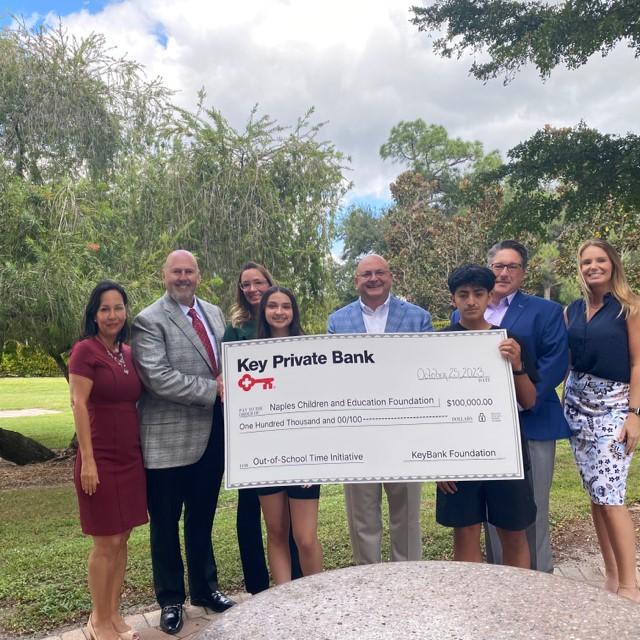 Naples Children & Education Foundaton CEO Maria Jimenez-Lara (far left) and Senior Director of education Programs Jamie Scott (far right), accept a KeyBank Foundation grant from Key Private Bank leaders (from left) Sr Fiduciary Strategist Phil Loiacano, Associate Relationship Manager Edenys Deynes, Market President Michael Schneider, and Sr Portfoliio Strategist Jim Bitonte. Also pictured are students in the program Jenny and Orlando. " "