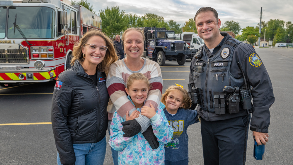 A family and police officer, a fire truck in the background