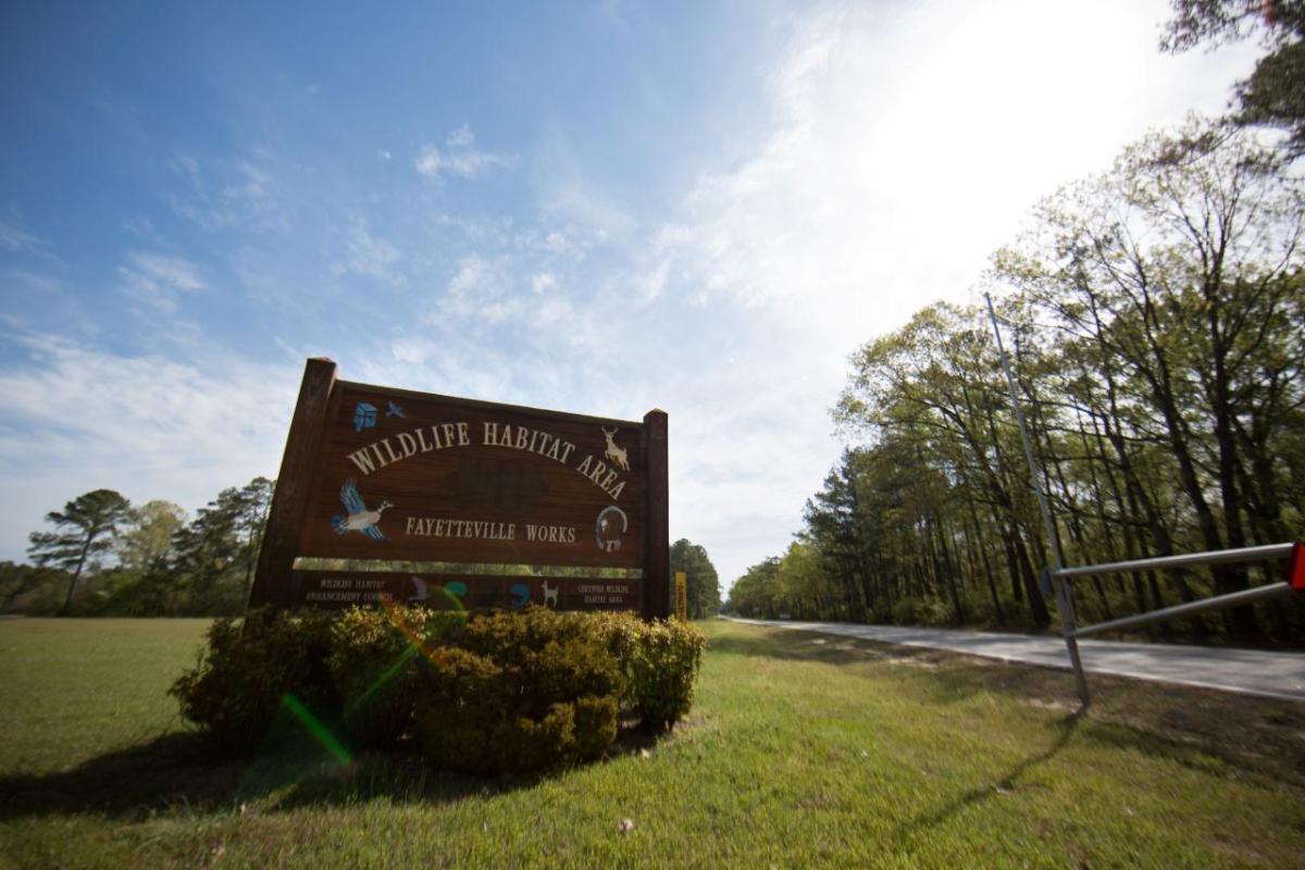 "Wildlife Habitat Area" sign at a gate on a long road.