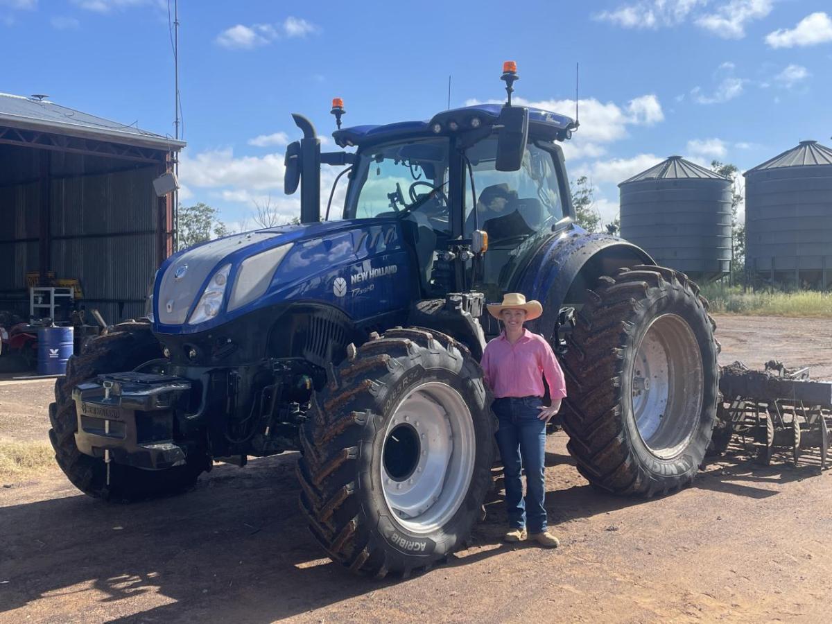 A person standing by a large tractor outside.