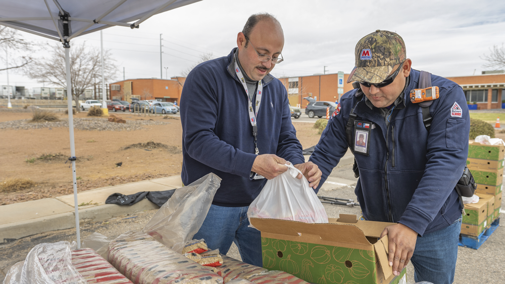 Two people stood at a table helping pack food bags