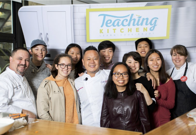 Students in a Chartwells Higher Ed teaching kitchen with Waste Warrior Chef Jet.