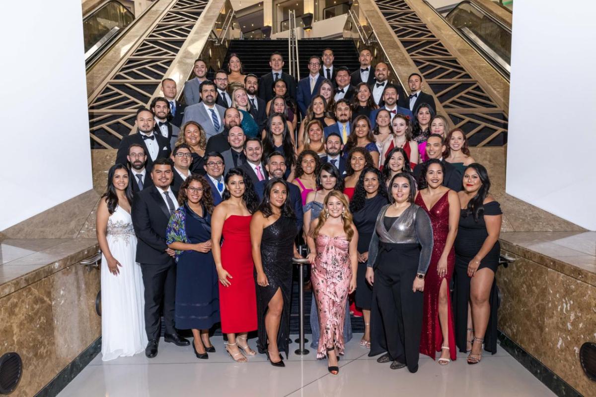 More than 50 people standing at the base of stairs wearing formal attire