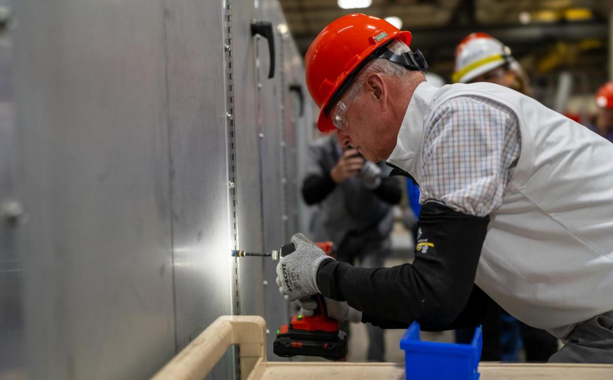 Congressman Steve Womack drills in a sheet metal screw on a custom air handling system at the Trane Fort Smith plant