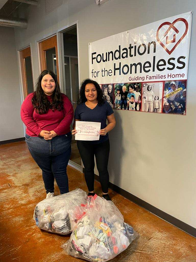 Two people standing behind donation to Foundation for the Homeless