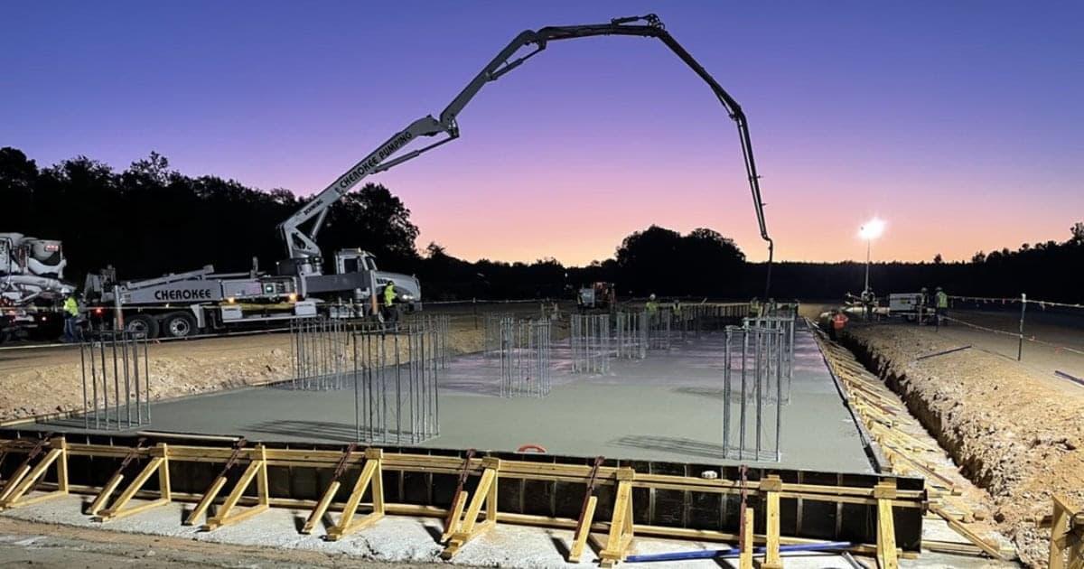 Framing around wet concrete and trucks in the distance.