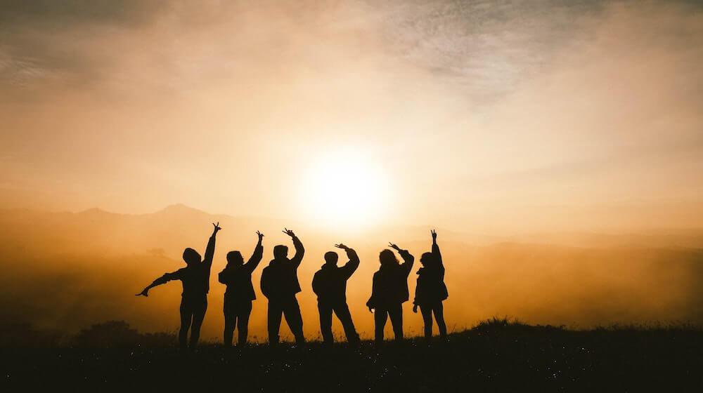 Silhouettes of young people against a setting sun.