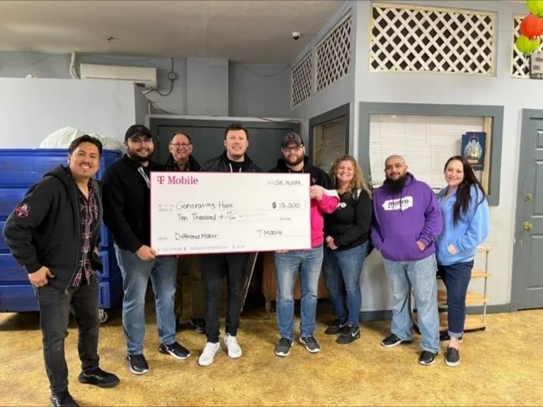 A group of people holding a donation cheque for the shelter Generating Hope