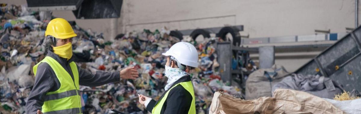 Two workers speaking in front of a landfill