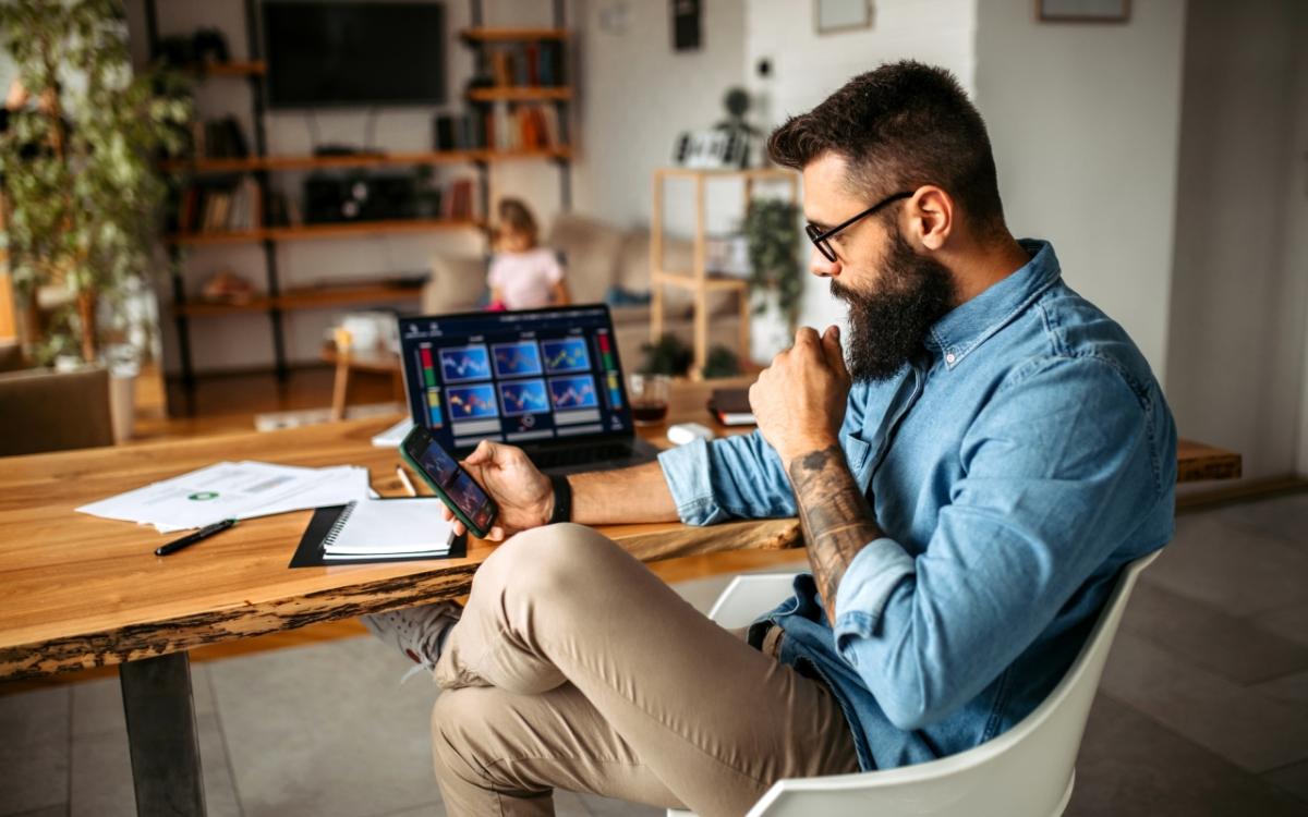 bearded man sitting at a desk looking at smartphone