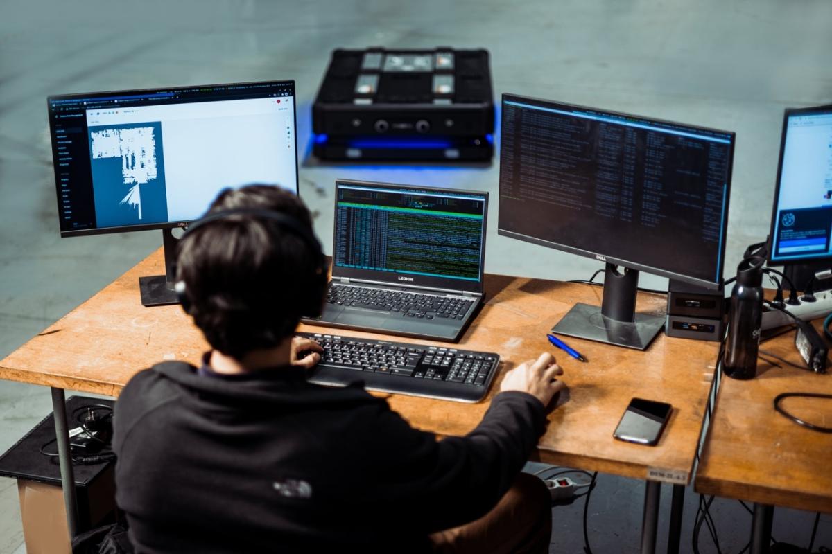 person sitting at a desk with many monitors