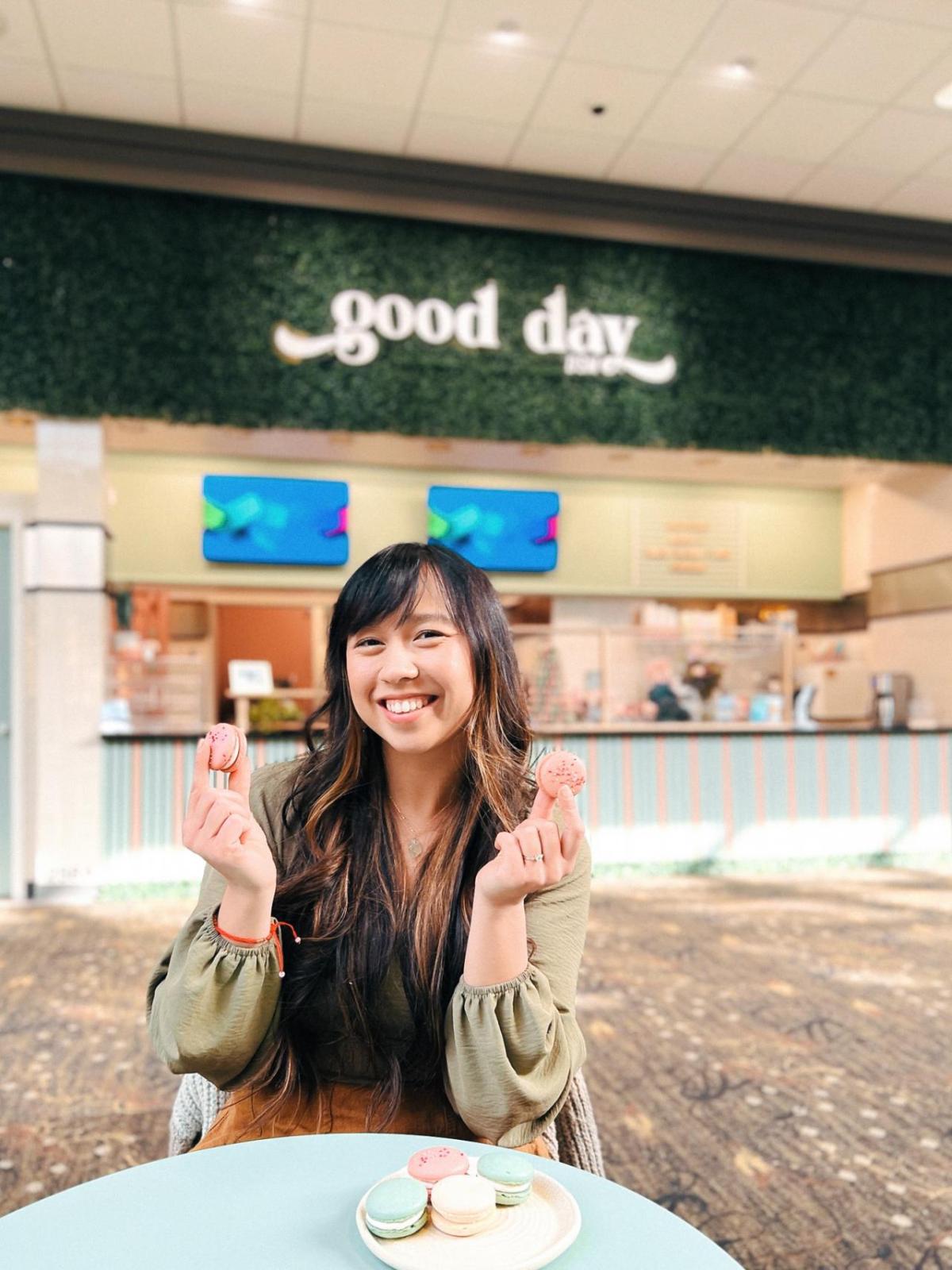 Anna Lam poses with colorful macarons in front of her bakery Good Day DSM.