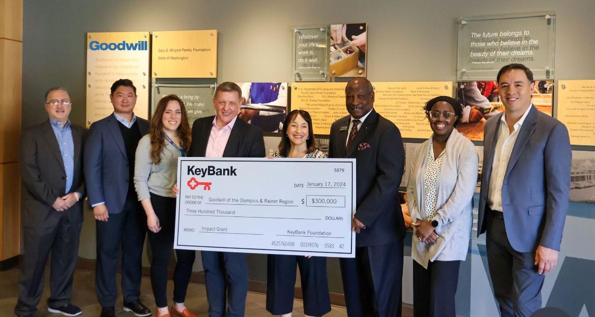 Teams from Goodwill of the Olympics and KeyBank shown with a $300,000 grant check.