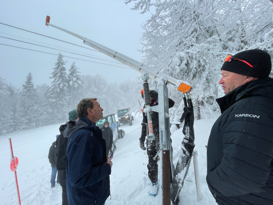 People outside on a snowy day next to snow-making equipment