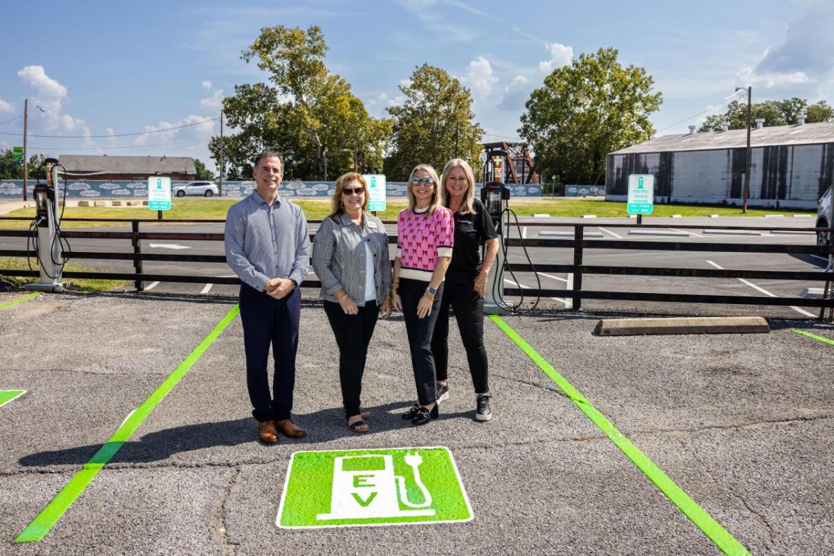 Four people stood together in an electric vehicle charger parking space 