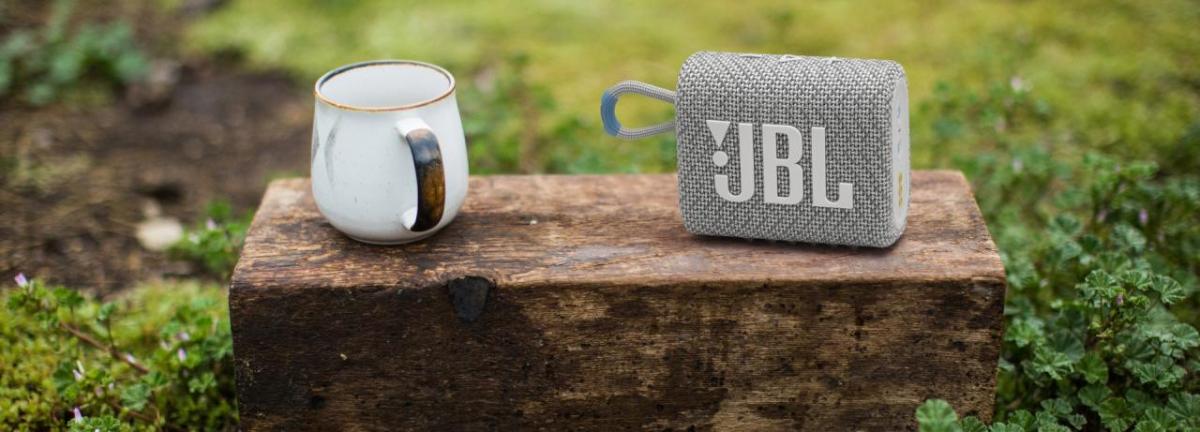 Coffee cup and JBL speaker shown in a grassy field.