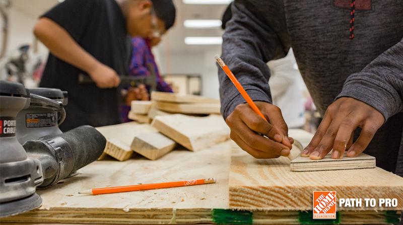 Two men shown working on a carpenter's bench.