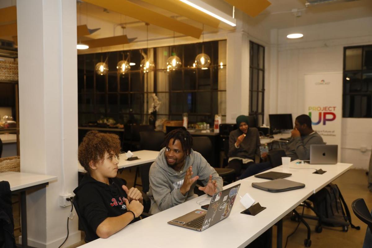 two people sitting in front of laptop