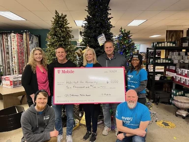 A group of people stood together holding a donation cheque for Habitat for Humanity (SKKC)