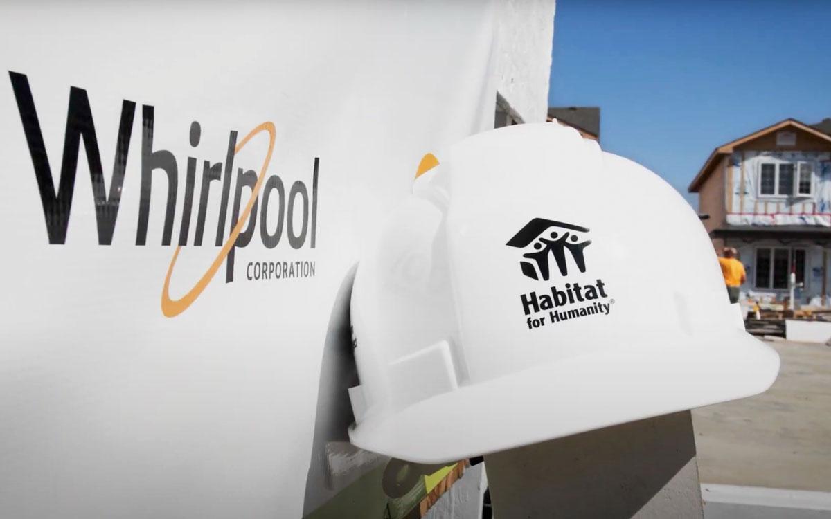 hard hat with habitat for humanity logo next to a whirlpool logo on a vehicle