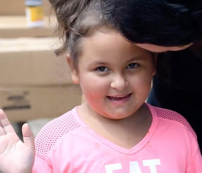 Young girl smiling and waving.