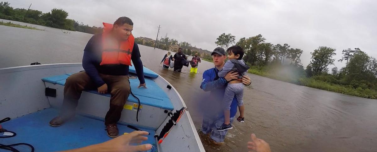 Chase McKinney carries a young boy to safety from the floodwaters in northeast Houston.