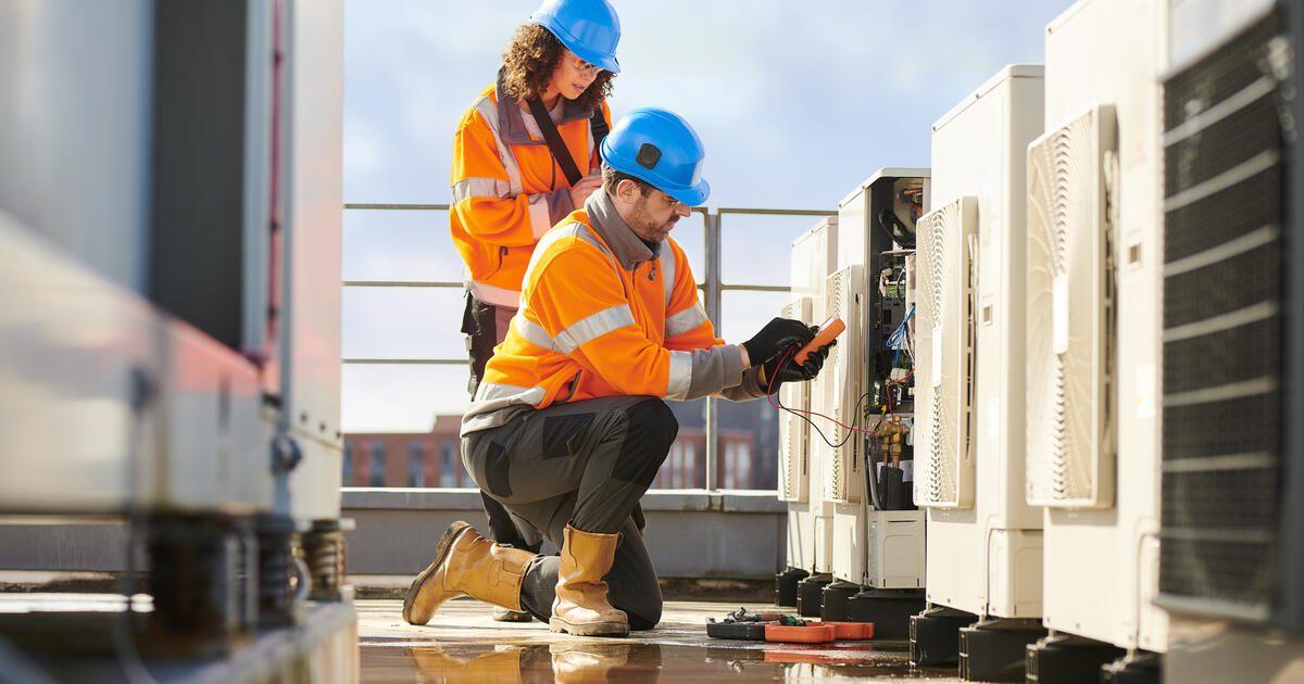 2 people working on a heat pump