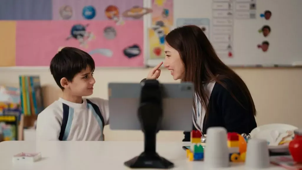 A child pointing to a teacher's nose