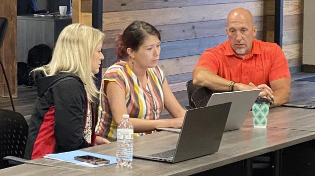 Three people sat at a table with laptops