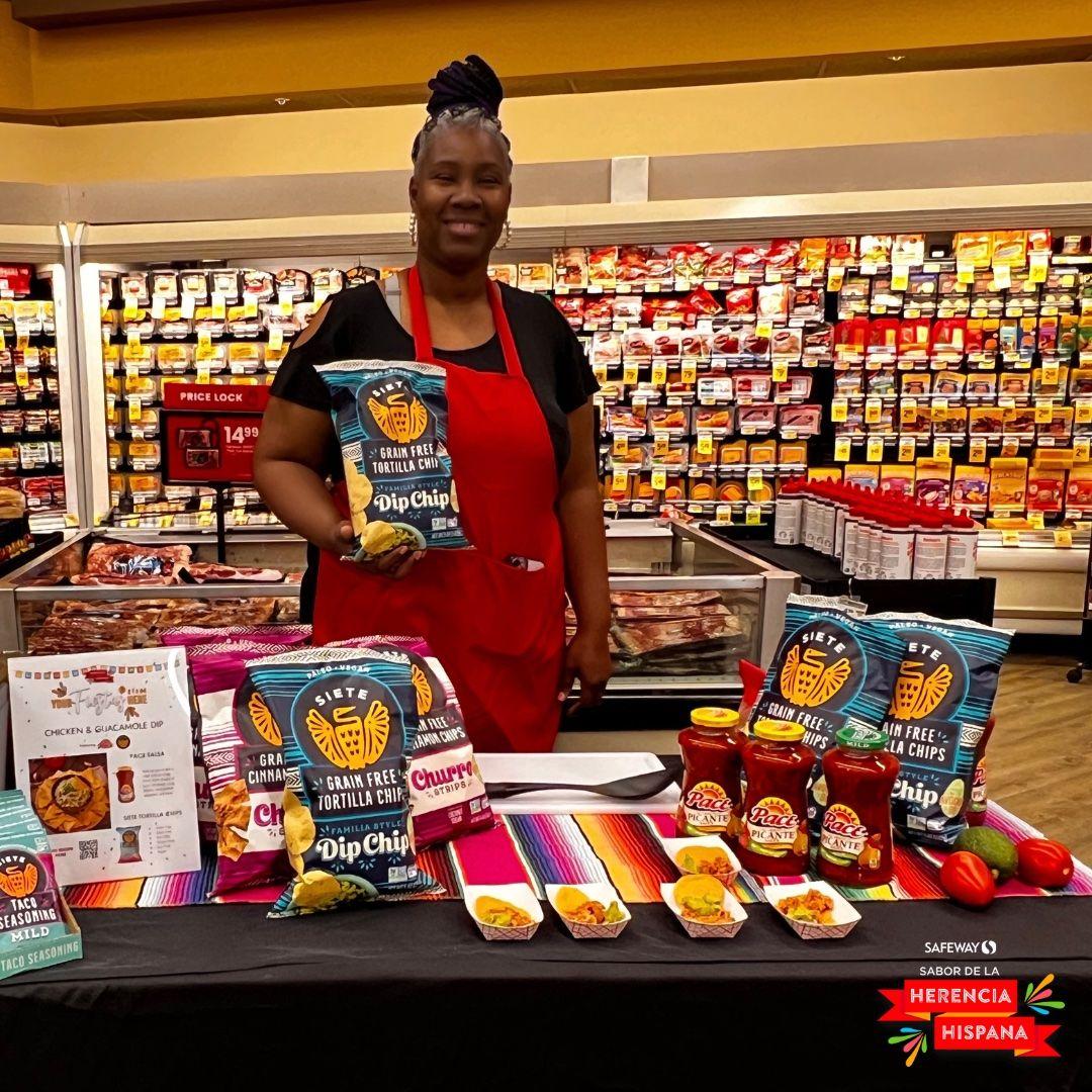 Photo of person standing at a display table inside a Safeway store with Hispanic Heritage Month grocery items.
