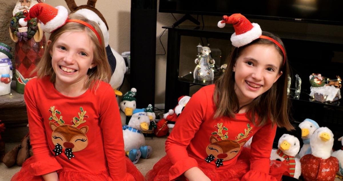 Young girls shown wearing reindeer pajamas with the Aflac Holiday Duck in the background.