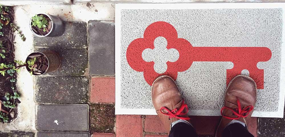 KeyBank logo welcome doormat. A person in boots is shown on the mat which has the red KeyBank logo.
