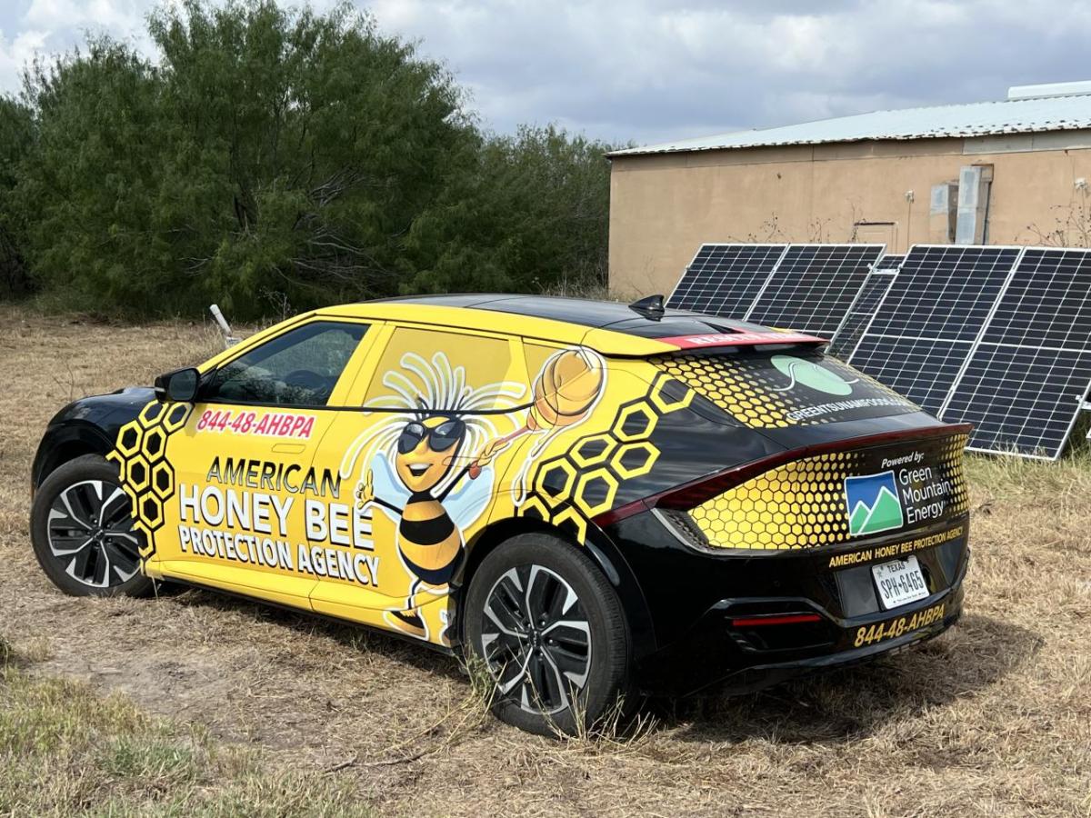 A grant of more than $200,000 from Green Mountain Energy Sun Club funded a 54-kW solar array and two KIA EV6 electric vehicles. Yellow and black KIA parked in front of ground-mounted solar array