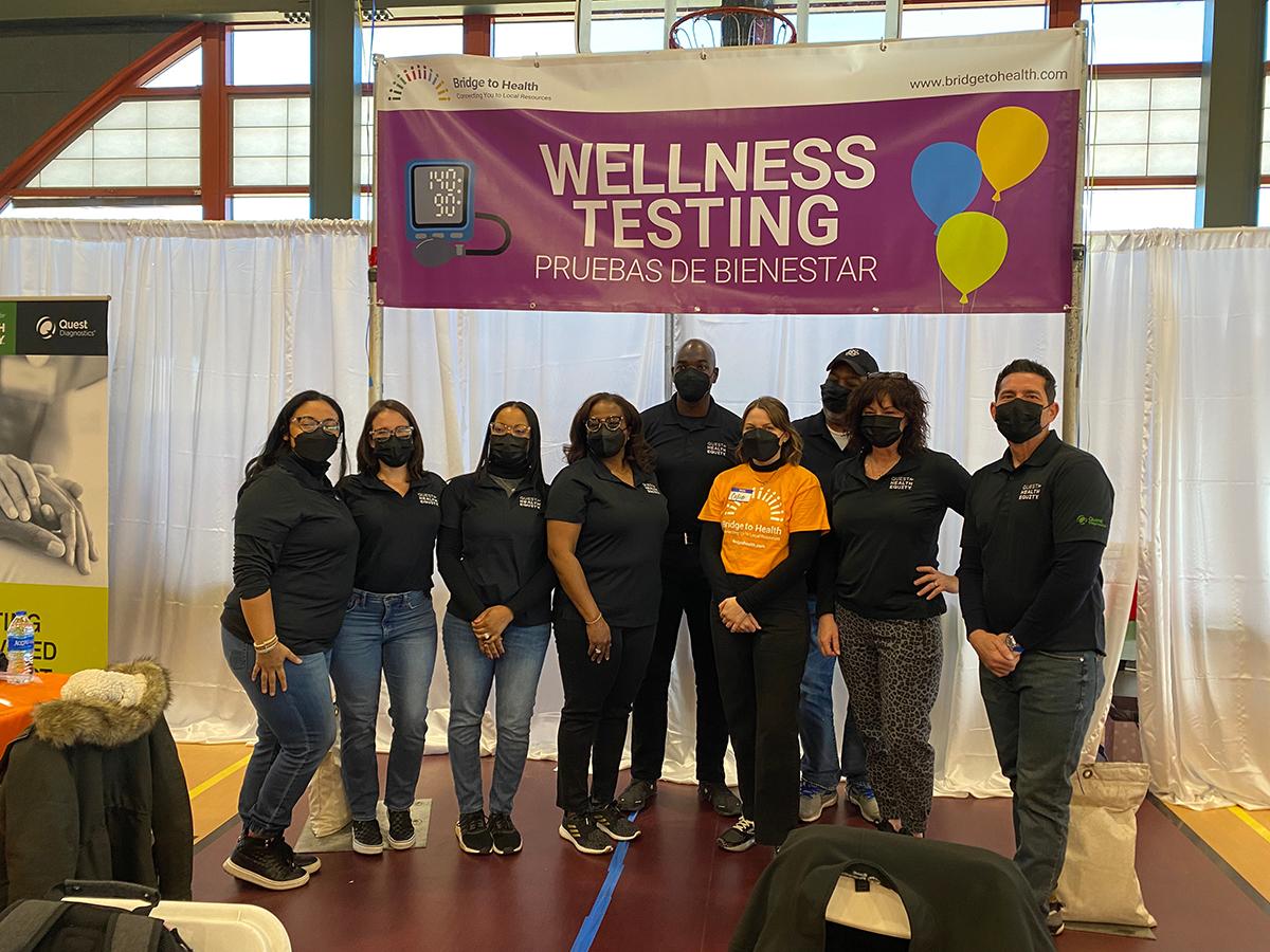 group of people under a banner saying "wellness testing"