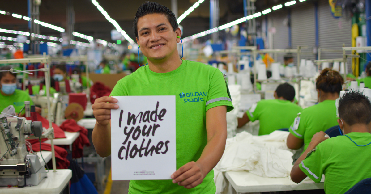 Person holding a sign that says "I made your clothes"