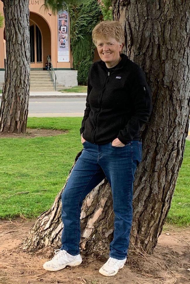 Photo of Shannon Whitmore leaning against a tree.