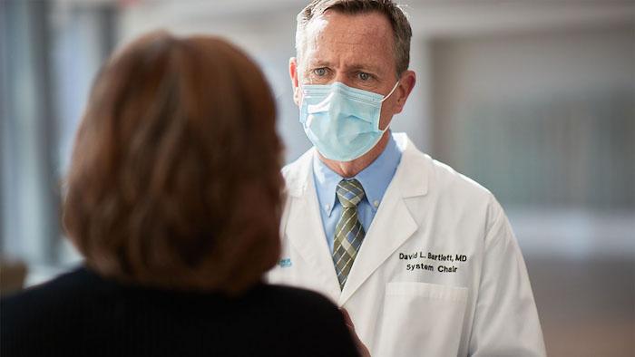 Masked Health Care Professional consulting with a female patient.