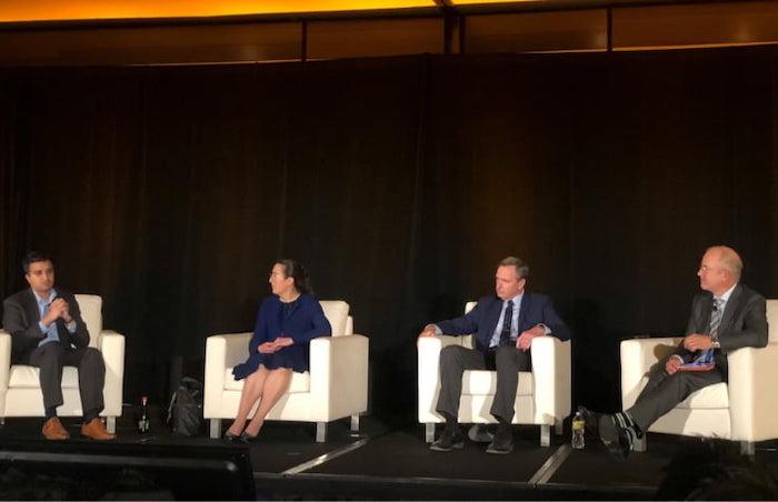 Panel of oncology specialists seated at a conference.