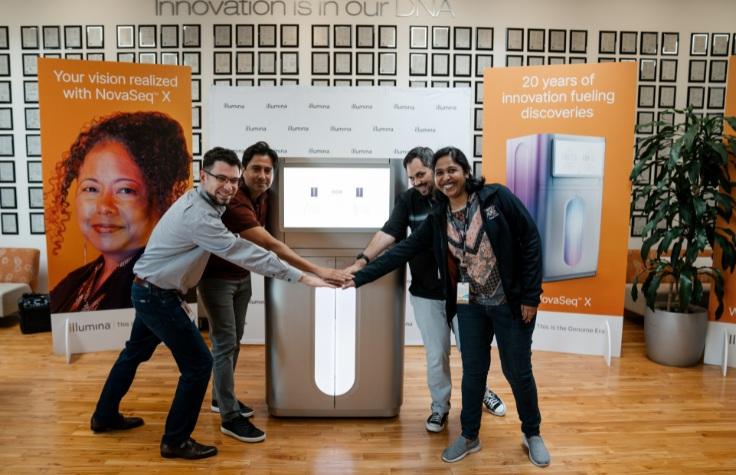 In front of the patent wall at Illumina's San Diego headquarters, employees gather around the NovaSeq X Plus.