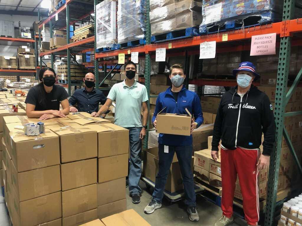 Submittable employees pack boxes at the Montana Food Bank Network. " "